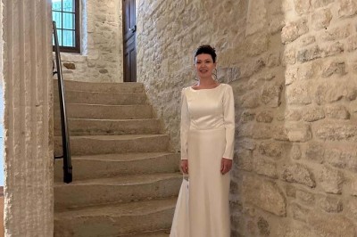 Tables élégamment dressées avec nappes blanches, serviettes pliées, verres et décorations florales dans une salle lumineuse.
