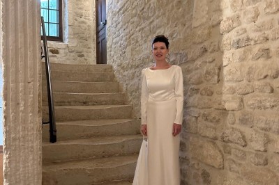 Tables élégamment dressées avec nappes blanches, serviettes pliées, verres et décorations florales dans une salle lumineuse.
