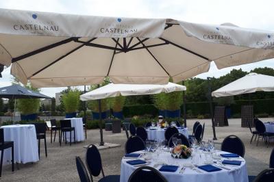 Salle de réception décorée avec des tables rondes, nappes blanches, rubans rouges et tonneaux en arrière-plan.