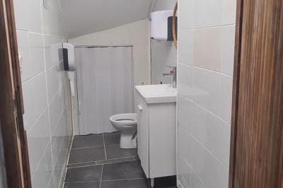 Toilettes modernes avec lavabo, miroir, distributeurs de savon et carrelage blanc et gris.