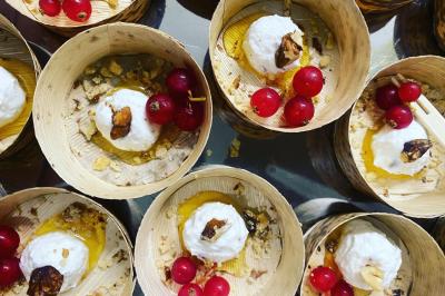 Buffet avec viennoiseries, fruits, jus et café, disposé sur une table recouverte d'une nappe rouge à carreaux.