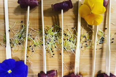 Buffet avec viennoiseries, fruits, jus et café, disposé sur une table recouverte d'une nappe rouge à carreaux.