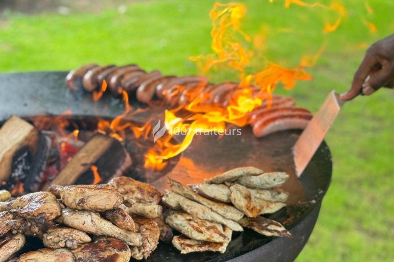 Viande et saucisses grillées sur un barbecue en plein air avec des flammes vives.