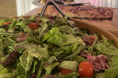 Buffet avec viennoiseries, fruits, jus et café, disposé sur une table recouverte d'une nappe rouge à carreaux.