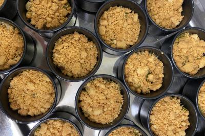 Buffet avec viennoiseries, fruits, jus et café, disposé sur une table recouverte d'une nappe rouge à carreaux.