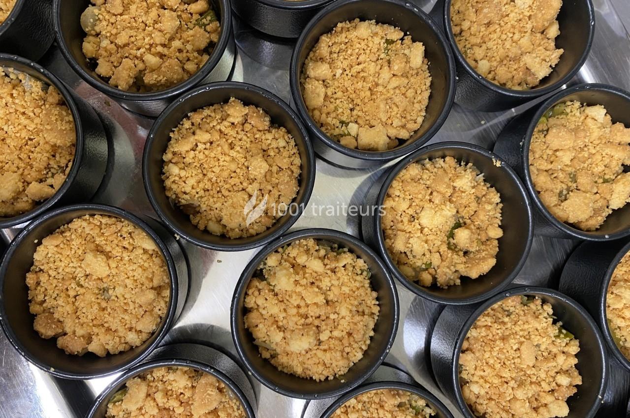 Desserts individuels au crumble doré, présentés dans des ramequins noirs sur une surface métallique.