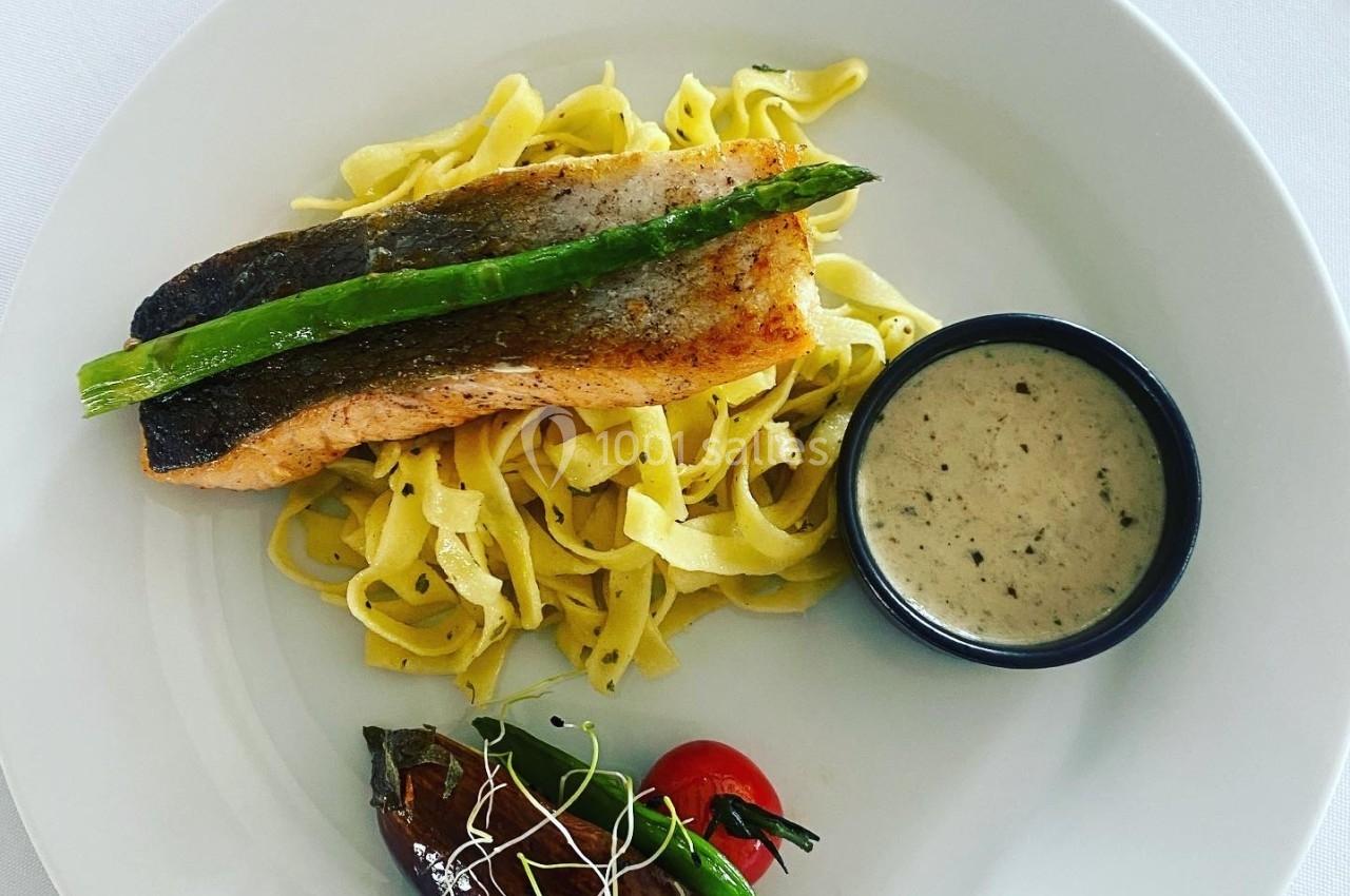 Assiette avec filet de saumon grillé sur tagliatelles, sauce en ramequin, tomate cerise et aubergine garnie.