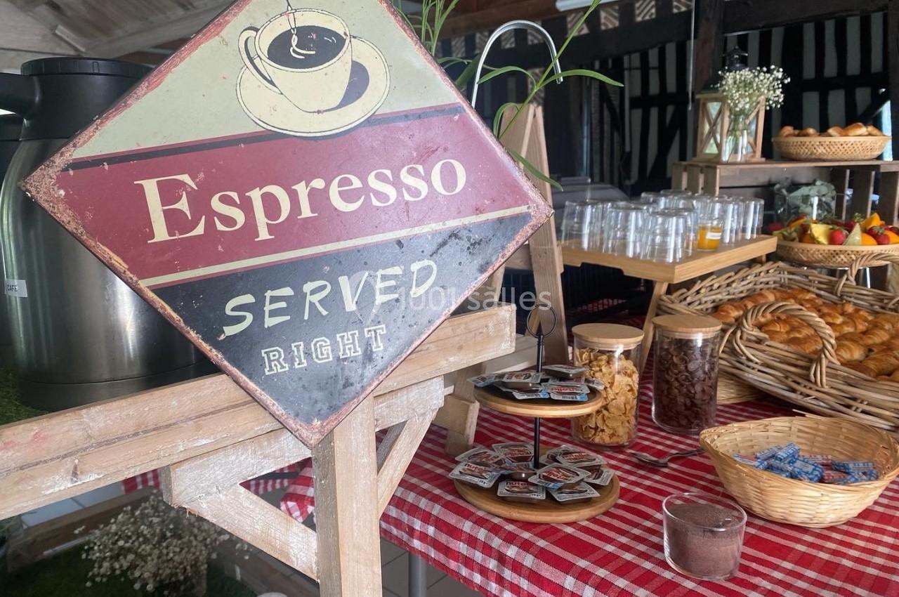 Stand de boissons et viennoiseries avec une pancarte ’Espresso Served Right’ sur une nappe à carreaux rouges.