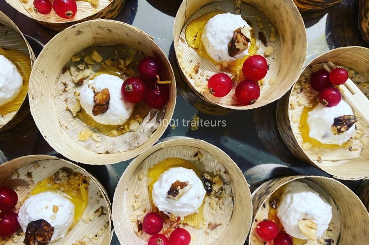 Desserts servis dans des bols en bois, composés de crème, groseilles rouges, miel et éclats de noix.