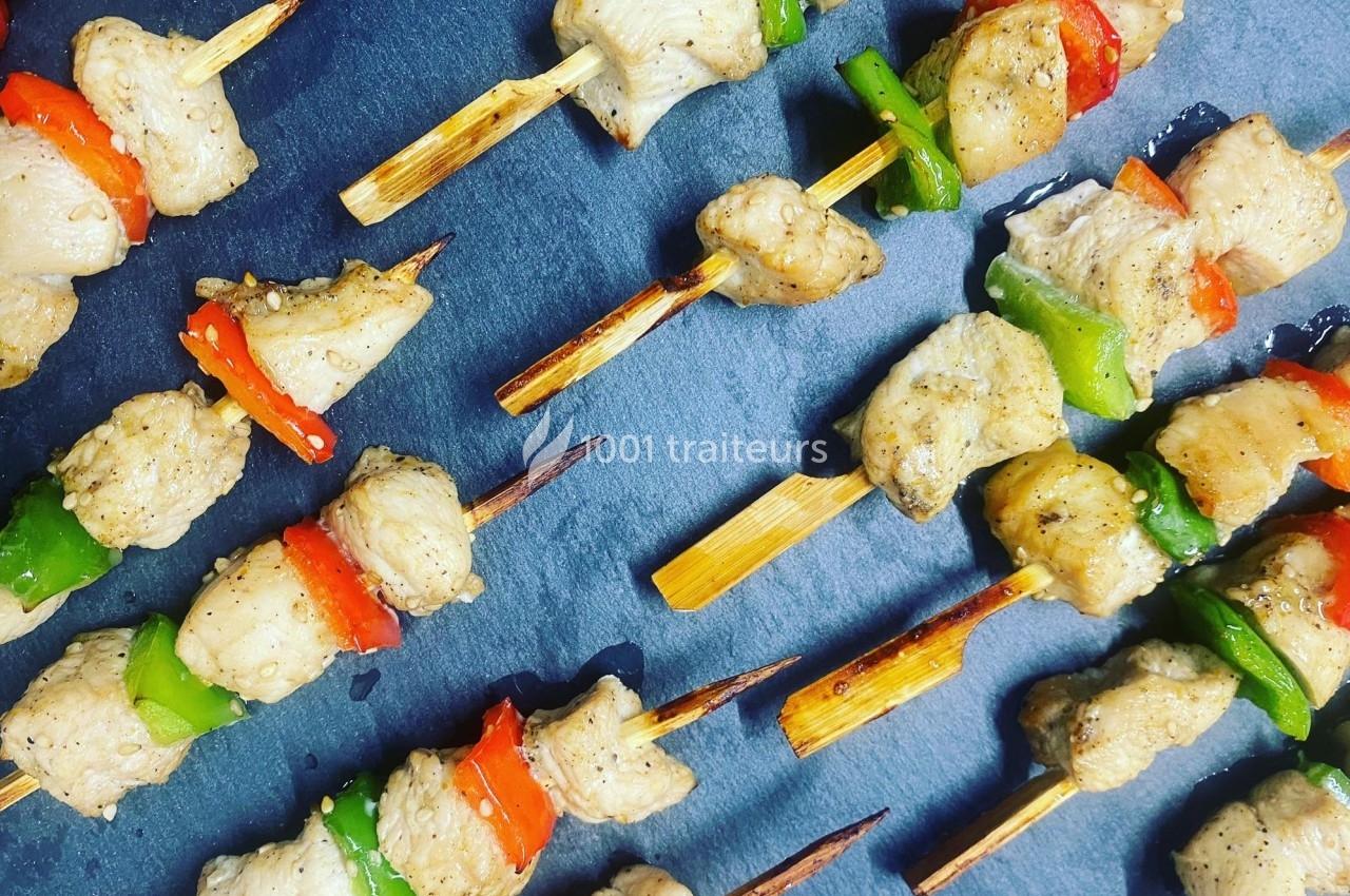 Brochettes de poulet grillé avec morceaux de poivrons rouges et verts, disposées sur une surface sombre.