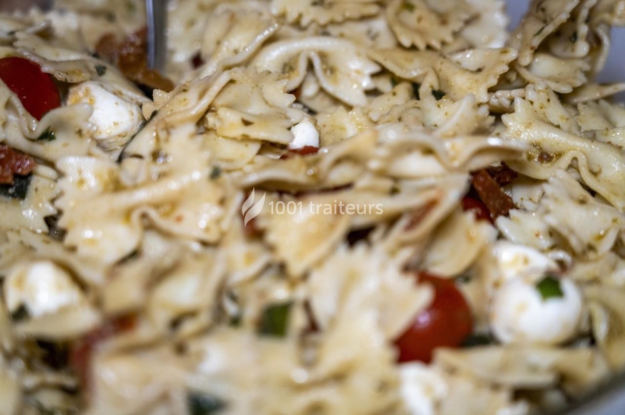 Salade de pâtes farfalle avec tomates cerises, billes de mozzarella et herbes fraîches, assaisonnée d'huile.