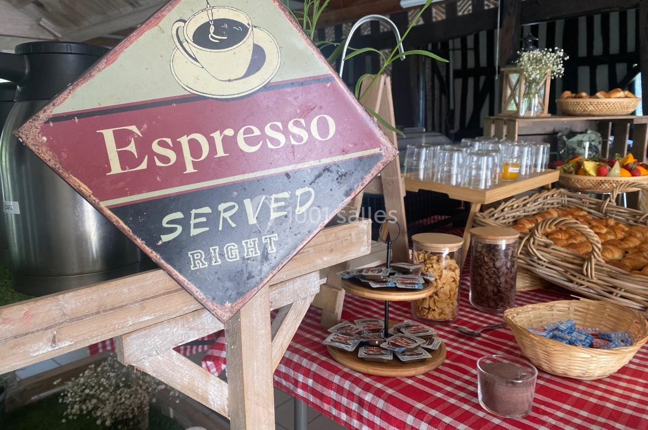 Stand de boissons et viennoiseries avec un panneau ’Espresso Served Right’ sur une table à nappe rouge et blanche.