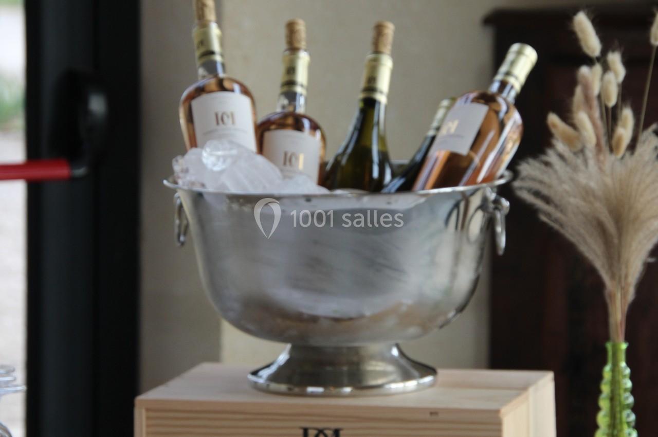 Bouteilles de vin blanc et rosé dans un seau à glace en métal, posées sur une caisse en bois, décor de table élégant.