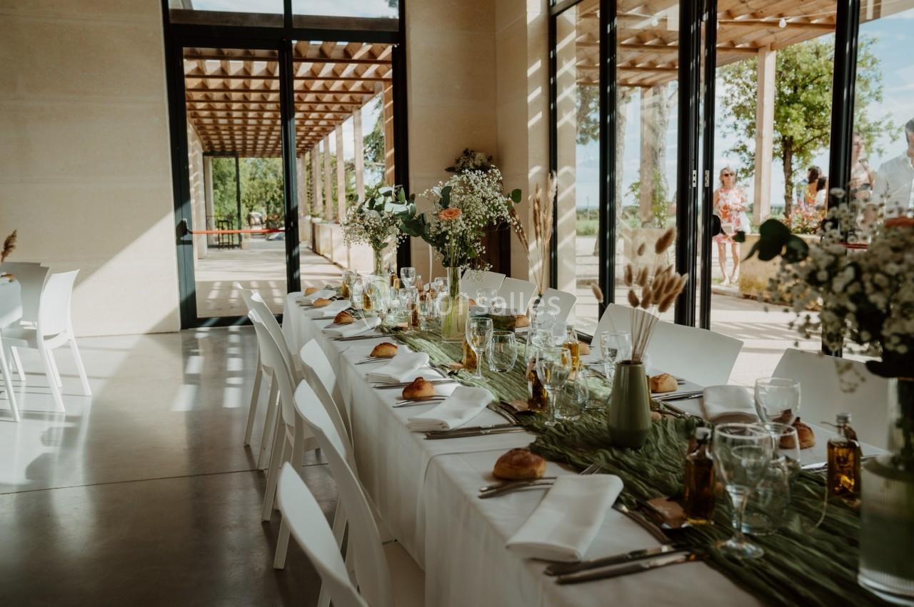 Table dressée pour un repas, décorée avec des fleurs et des éléments naturels, dans une salle lumineuse avec vue sur l…