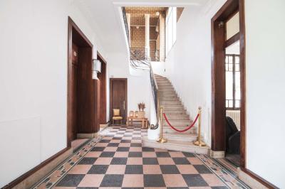 Salle lumineuse décorée pour un événement, avec des tables dressées, des chaises dorées et des fleurs en centre de table.