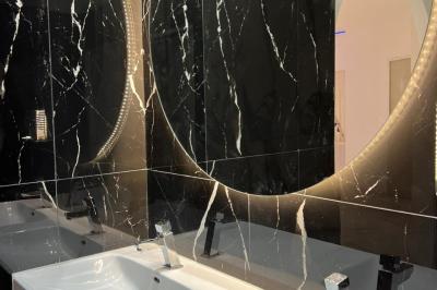 Lavabos modernes avec miroirs ronds rétroéclairés, entourés de murs en marbre noir veiné de blanc.