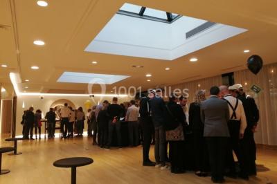 Terrasse extérieure avec pelouse artificielle, pergola couverte et immeubles en arrière-plan par temps ensoleillé.