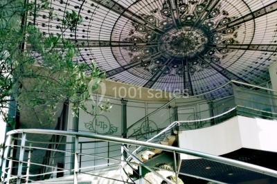 Terrasse extérieure avec pelouse artificielle, pergola couverte et immeubles en arrière-plan par temps ensoleillé.