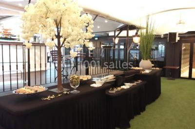 Terrasse extérieure avec pelouse artificielle, pergola couverte et immeubles en arrière-plan par temps ensoleillé.