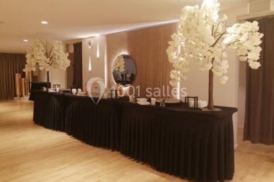 Terrasse extérieure avec pelouse artificielle, pergola couverte et immeubles en arrière-plan par temps ensoleillé.