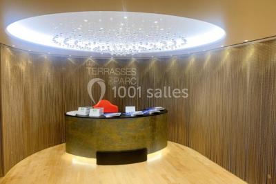 Terrasse extérieure avec pelouse artificielle, pergola couverte et immeubles en arrière-plan par temps ensoleillé.