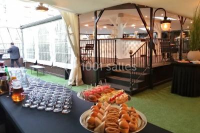 Terrasse extérieure avec pelouse artificielle, pergola couverte et immeubles en arrière-plan par temps ensoleillé.