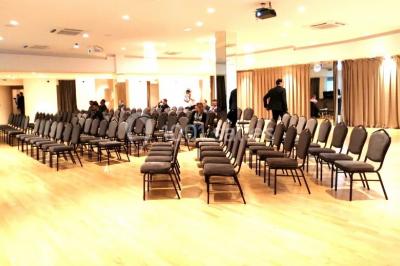 Terrasse extérieure avec pelouse artificielle, pergola couverte et immeubles en arrière-plan par temps ensoleillé.