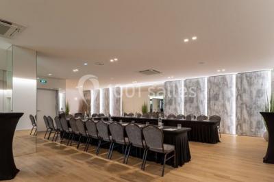 Terrasse extérieure avec pelouse artificielle, pergola couverte et immeubles en arrière-plan par temps ensoleillé.