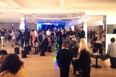 Terrasse extérieure avec pelouse artificielle, pergola couverte et immeubles en arrière-plan par temps ensoleillé.