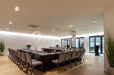 Terrasse extérieure avec pelouse artificielle, pergola couverte et immeubles en arrière-plan par temps ensoleillé.