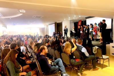 Terrasse extérieure avec pelouse artificielle, pergola couverte et immeubles en arrière-plan par temps ensoleillé.