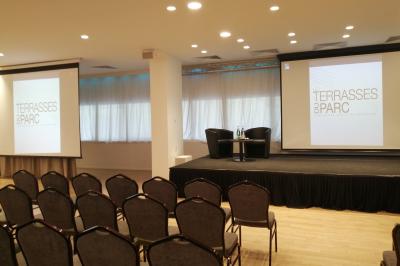 Terrasse extérieure avec pelouse artificielle, pergola couverte et immeubles en arrière-plan par temps ensoleillé.