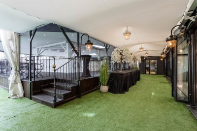 Salle de conférence avec des rangées de chaises noires alignées face à une scène et un écran de projection.