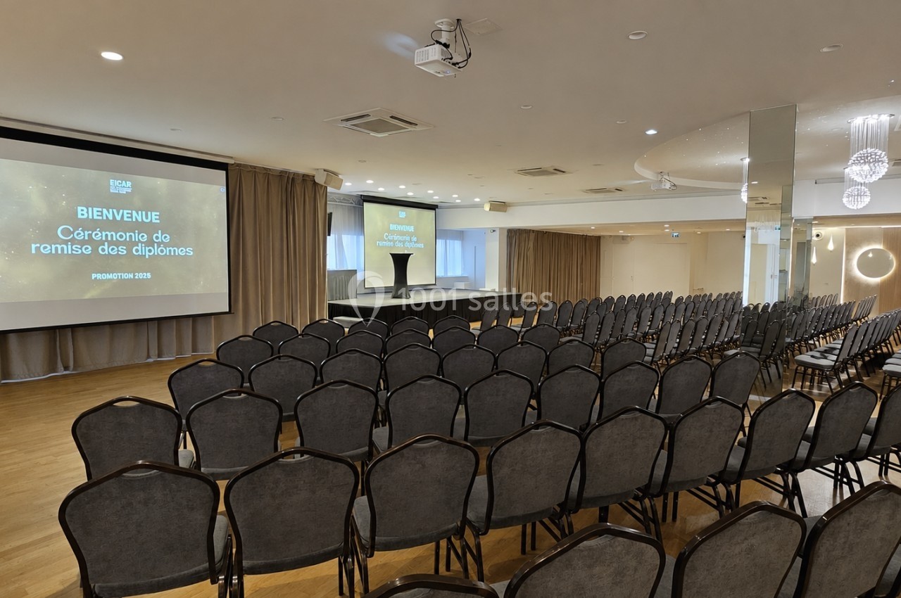 Salle de conférence aménagée avec des rangées de chaises et un écran affichant ’Cérémonia de remise des diplômes’.