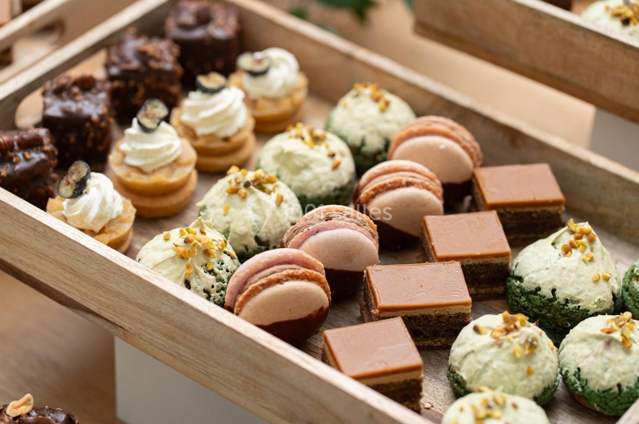 Plateau en bois contenant un assortiment de pâtisseries variées, dont macarons, gâteaux et choux garnis.