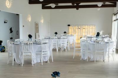 Table élégamment dressée avec nappes blanches, verres, couverts, bouquets de fleurs et petits pots décoratifs.