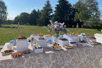 Table élégamment dressée avec nappes blanches, verres, couverts, bouquets de fleurs et petits pots décoratifs.