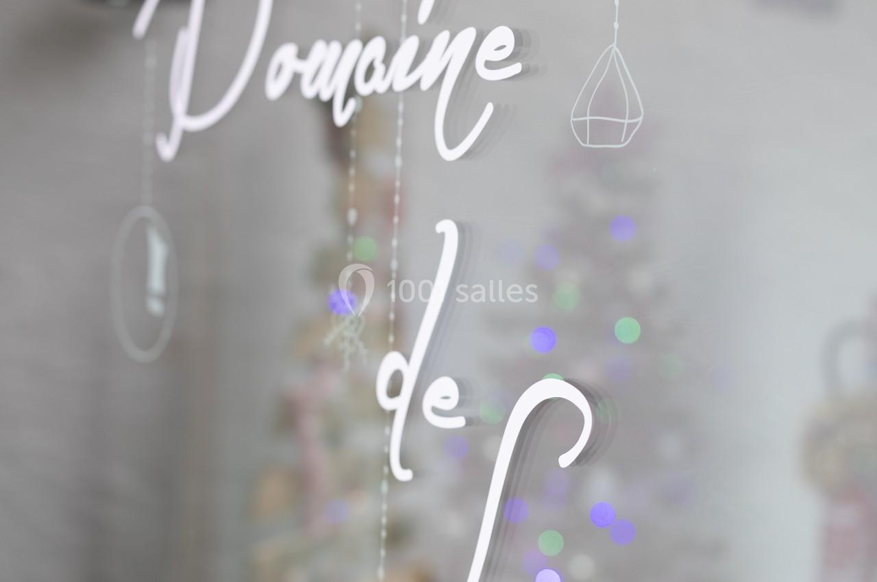 Texte ’Domaine de Lasea’ inscrit sur une vitre, avec un sapin de Noël flou en arrière-plan.