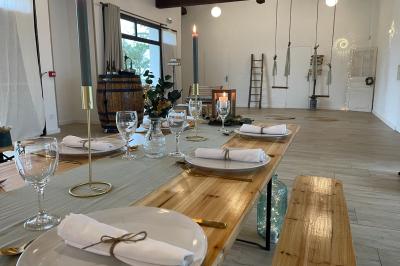 Table élégamment dressée avec nappes blanches, verres, couverts, bouquets de fleurs et petits pots décoratifs.