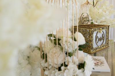 Table élégamment dressée avec nappes blanches, verres, couverts, bouquets de fleurs et petits pots décoratifs.