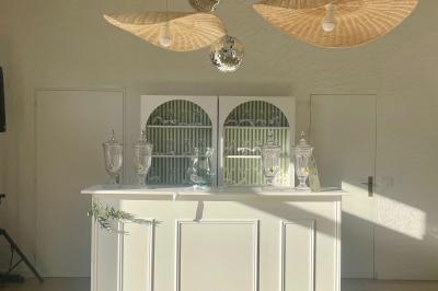 Table élégamment dressée avec nappes blanches, verres, couverts, bouquets de fleurs et petits pots décoratifs.