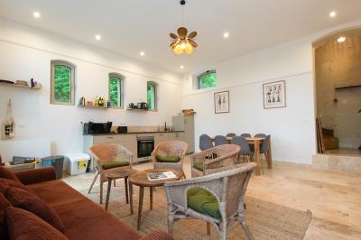 Canapé en velours brun devant une grande fenêtre lumineuse, entouré de rideaux beiges et de meubles en bois.