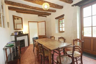 Canapé en velours brun devant une grande fenêtre lumineuse, entouré de rideaux beiges et de meubles en bois.