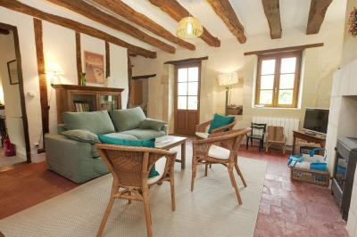 Canapé en velours brun devant une grande fenêtre lumineuse, entouré de rideaux beiges et de meubles en bois.