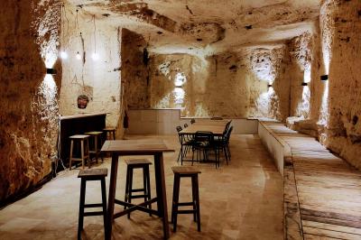 Canapé en velours brun devant une grande fenêtre lumineuse, entouré de rideaux beiges et de meubles en bois.