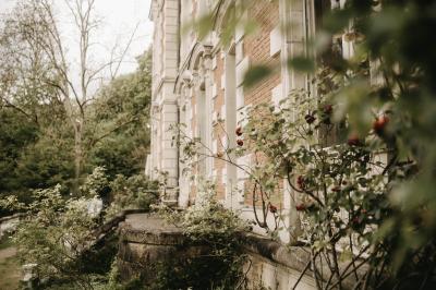 Canapé en velours brun devant une grande fenêtre lumineuse, entouré de rideaux beiges et de meubles en bois.