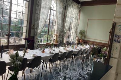 Canapé en velours brun devant une grande fenêtre lumineuse, entouré de rideaux beiges et de meubles en bois.