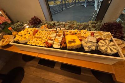 Plateau de fromages variés avec fruits secs, raisins et condiments, disposé sur une table en bois décorée de feuillage.