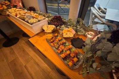 Plateau de fromages variés avec fruits secs, raisins et condiments, disposé sur une table en bois décorée de feuillage.