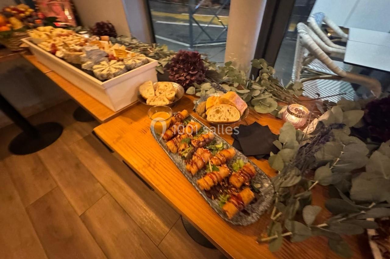Buffet disposé sur une table en bois, avec des plats variés, des décorations végétales et une vue sur l'extérieur.